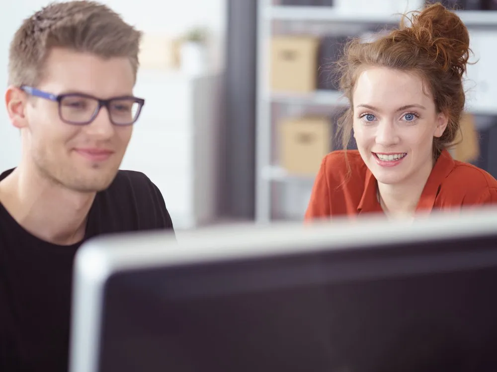 Zwei Mitarbeitende gemeinsam am Bildschirm: Akzeptanz im Team als Fundament erfolgreicher Digitalisierung